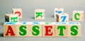 Wooden blocks with the word Assets and randomly scattered cubes. Resource owned by the business. Financial accounting. Money and