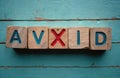 Wooden blocks with word AVOID including red cross instead of letter X. Symbol of problem solving, strategy development, finding Royalty Free Stock Photo