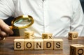 Wooden blocks with the word Bonds and businessman. A bond is a security that indicates that the investor has provided a loan to