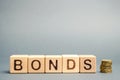 Wooden blocks with the word Bonds and coins. A bond is a security that indicates that the investor has provided a loan to the Royalty Free Stock Photo