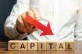 Wooden blocks with the word Capital and arrow down in the hands of a businessman. The concept of the fall in the level of Royalty Free Stock Photo