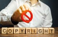 Wooden blocks with the word Copyright and the prohibition sign in the hands of a businessman. Patenting. Copyright protection.