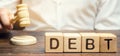 Wooden blocks with the word Debt and judge with a gavel. The concept of judicial punishment for non-payment of debt. Property