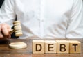Wooden Blocks With The Word Debt And Judge With A Gavel. The Concept Of Judicial Punishment For Non-payment Of Debt. Property
