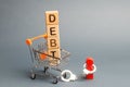 Wooden blocks with the word Debt in a supermarket trolley and a human figurine bound by handcuffs. Mandatory payment of debt.