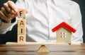 Wooden blocks with the word Fair and a wooden house. Fair value of real estate and housing. Property valuation. Home appraisal. Royalty Free Stock Photo