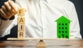 Wooden blocks with the word Fair and a wooden house. Fair value of real estate and housing. Property valuation. Home appraisal. Royalty Free Stock Photo