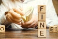 Wooden blocks with the word Fine and the man calculates the size of the fine. The concept of financial punishment. Penalty as a Royalty Free Stock Photo