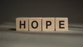 A wooden blocks with the word HOPE written on  it on a gray background Royalty Free Stock Photo