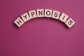 Wooden blocks with word HYPNOSIS on magenta background