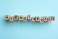 Wooden blocks with word HYPNOTHERAPY on blue background, flat lay