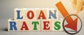 Wooden blocks with the word Loan rates and arrow down. The concept of low mortgage rates. Real estate market. Housing. Credit.