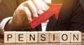 Wooden blocks with the word Pension and up arrow. Improving the financial condition of older people. Surcharge and pension