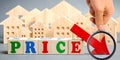 Wooden blocks with the word Price, down arrow and wooden houses. The concept of low cost real estate. Lower mortgage interest Royalty Free Stock Photo