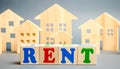 Wooden blocks with the word Rent and wooden houses. The concept of renting housing and real estate. The cost of a rented home or