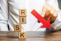 Wooden blocks with the word Risk and a down arrow. Reduce financial risk for investment and capital. Protection of investment