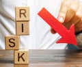 Wooden blocks with the word Risk and a down arrow. Reduce financial risk for investment and capital. Protection of investment Royalty Free Stock Photo