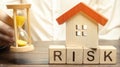 Wooden blocks with the word Risk, the house and the clock. The concept of non-payment of interest rates on mortgages. Real estate