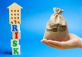 Wooden blocks with the word Risk and a miniature house with money bag. Real estate investment risks. Risky investments. Loss of Royalty Free Stock Photo