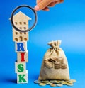 Wooden blocks with the word Risk and a miniature house with a money bag. Real estate investment risk. Risky investments. Loss of