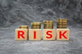 Wooden blocks with the word risk and money coin stack on dark background. Financial debt decrease concept Royalty Free Stock Photo