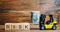 Wooden blocks with the word Risk, money and a forklift. Financial and commercial risk concept. Investing in a business. Risks