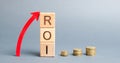 Wooden blocks with the word ROI and arrow up. High level of business profitability. Return on investment, invested capital, rate.