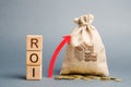 Wooden blocks with the word ROI and the up arrow with the money bag. High level of business profitability. Return on investment,