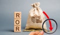 Wooden blocks with the word ROR, money bag and down arrow. Financial ratio illustrating the level of business loss. Return on