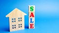 Wooden blocks with the word Sale and wooden miniature house. The concept of the sell of real estate, apartments and residential Royalty Free Stock Photo