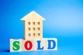 Wooden blocks with the word Sold and wooden miniature house. The concept of the sell of real estate, apartments and residential Royalty Free Stock Photo