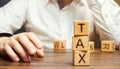 Wooden blocks with the word tax and a businessman sitting at the table. Making the right decision. Time to pay taxes. The concept Royalty Free Stock Photo