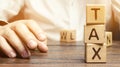 Wooden blocks with the word tax and a businessman sitting at the table. Making the right decision. Time to pay taxes. The concept