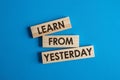 Wooden blocks with the words Learn From Yesterday on a blue background Royalty Free Stock Photo