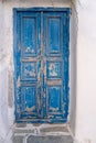 Wooden blue color shabby door on a whitewashed wall. Greece, Cyclades