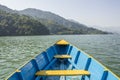 A wooden blue yellow boat on the lake against the background of green mountains