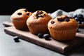 Wooden board with blueberry muffins on grey table against black background Royalty Free Stock Photo