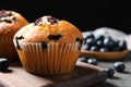 Wooden board with blueberry muffins on grey table against black background, closeup view Royalty Free Stock Photo