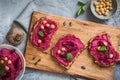 Wooden board of bread slices with beetroot hummus on a gray background, healthy vegan food Royalty Free Stock Photo