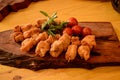 A wooden board with breaded chicken skewers, cherry tomatoes and sprigs of basil and rosemary Royalty Free Stock Photo