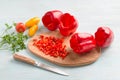 Wooden board with chopped red bell peppers, whole peeled bell peppers, tomatoes and parsley on a light blue background with Royalty Free Stock Photo