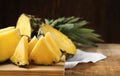 Wooden board with cut ripe pineapple on table, closeup