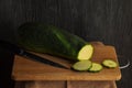 On a wooden board for cutting products is a green courgette and a ceramic knife Royalty Free Stock Photo