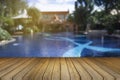 Wooden board empty table against of blurred swimming pool background. Perspective brown wood over swimming pool Royalty Free Stock Photo