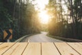 Wooden board empty table in front of blurred background. Perspective brown wood over road is surrounded by pine trees forest to th