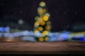 Wooden board empty table in front of blurred Christmas tree and garlands of lights background evening. Royalty Free Stock Photo