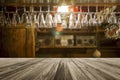 Wooden board empty table in front of blurred glass hanging upside down on a shelf at bar background Royalty Free Stock Photo