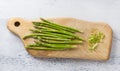 Wooden board of fresh asparagus with cut tough pieces on a light blue background, home cooking Royalty Free Stock Photo