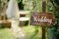 Wooden board with the inscription in paint Wedding. Sign for guests at the entrance, outdoors wedding ceremony decoration. Hand Royalty Free Stock Photo