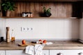 wooden board with knife, olive oil, tomatoes, towel on modern kitchen countertop and shelf with spices and plants. cooking food. Royalty Free Stock Photo